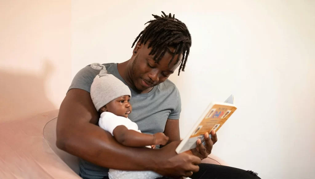 father reading a book with infant